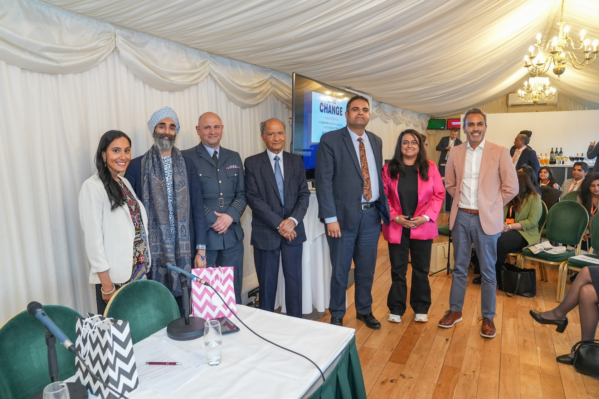 Asian Voice panellists and organisers standing together in front of the Be the Change screen at the House of Commons.